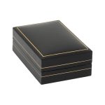 Box closed, A rectangular black leatherette jewelry box with a thin gold leaf line around the hinged lid and base. The inside features a removable black velvet pad for holding a chain pendant, and the inside lid has a white silk inlay printed in gold leaf with a scales logo and the text "City of London Jewellers".