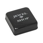 Picture of closed charm box, A small square black plastic box with slightly rounded corners and sparkling silver bits embedded in the material. The pull-off lid features the words "Jewel Shop" in white print at the top. The inside is lined with white cotton wool.