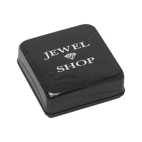 Picture of closed charm box, A small square black plastic box with slightly rounded corners and sparkling silver bits embedded in the material. The pull-off lid features the words "Jewel Shop" in white print at the top. The inside is lined with white cotton wool.