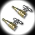 Sterling silver champagne bottle cufflinks with gold‑plated accents photographed on a deep black background, illuminated by a soft white spotlight that highlights their elegant contours and reflective shine.