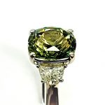 Extreme close‑up of the green sapphire and half‑moon diamonds.