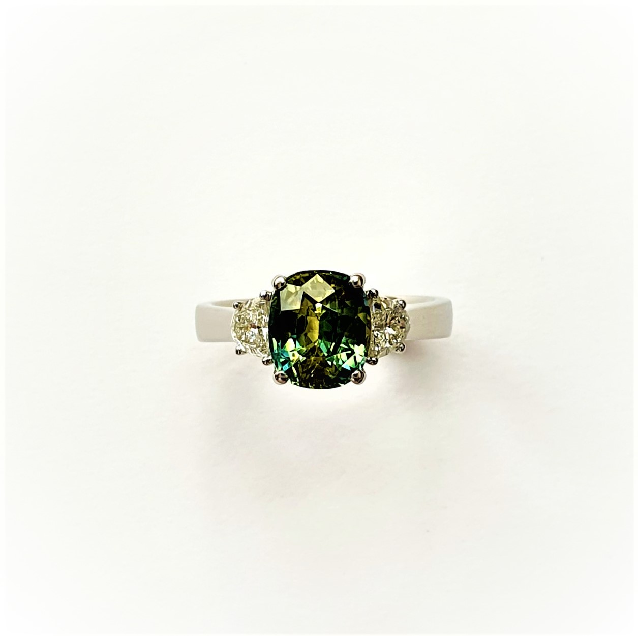 Top view of the platinum ring showing the green sapphire and half‑moon diamonds.
