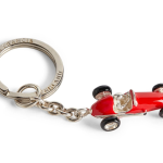 Close-up of red enamel racing car keyring crafted in sterling silver, featuring black enamel tyres and high-gloss finish.
