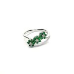 A captivating image of a Three Cluster Emerald Ring in 18ct white gold. The ring showcases three clusters of vibrant green emeralds, with six emeralds in each cluster. Adorning the ring shank is a graceful wave design, adding a touch of elegance to the overall aesthetic. The clusters are accentuated by three sparkling diamonds, positioned at the centre of each cluster." Flat top view.