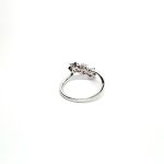 A captivating image of a Three Cluster Ruby Ring in 18ct white gold. The ring showcases three clusters of vibrant rubies, with six rubies in each cluster. Adorning the ring shank is a graceful wave design, adding a touch of elegance to the overall aesthetic. The clusters are accentuated by three sparkling diamonds, positioned at the centre of each cluster." Back view.