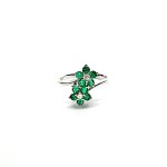 Double Cluster Emerald Ring. Crafted in 18ct white gold featuring two clusters of five round bright green emeralds with a single diamond to the centre of each cluster, with a wave cross over shank