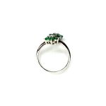 Double Cluster Emerald Ring. Crafted in 18ct white gold featuring two clusters of five round bright green emeralds with a single diamond to the centre of each cluster, with a wave cross over shank