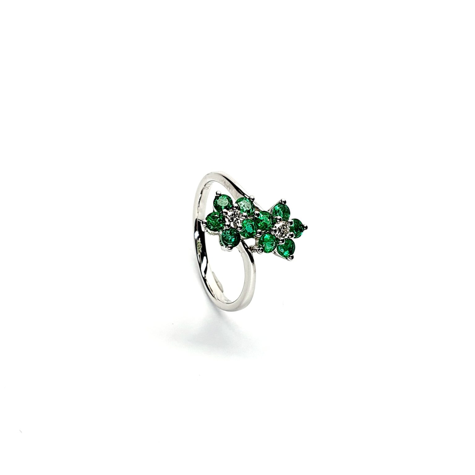 Double Cluster Emerald Ring. Crafted in 18ct white gold featuring two clusters of five round bright green emeralds with a single diamond to the centre of each cluster, with a wave cross over shank