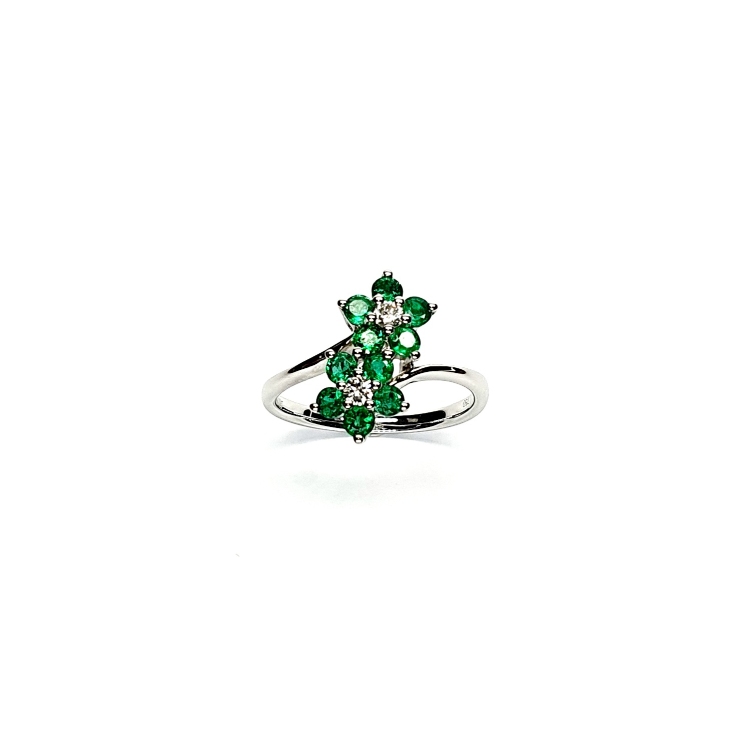 Double Cluster Emerald Ring. Crafted in 18ct white gold featuring two clusters of five round bright green emeralds with a single diamond to the centre of each cluster, with a wave cross over shank
