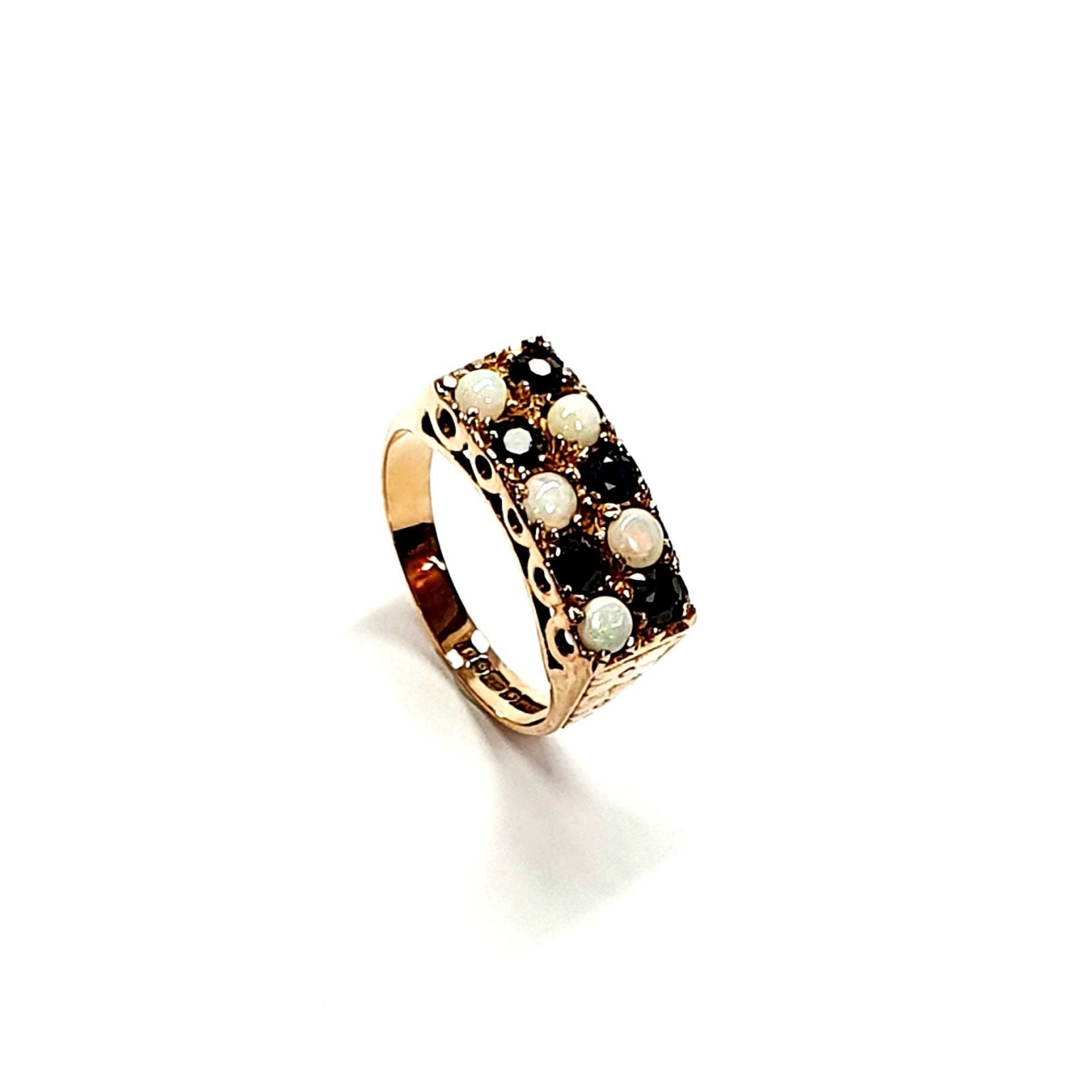 Vintage 1979 opal & dark blue sapphire 9ct gold landscape rectangular top ring measuring 18mm x 7.8mm set with five round cabochon cut opals & five round dark blue sapphires in a chequer formation with three hand engraved flowers to both—side shoulders.