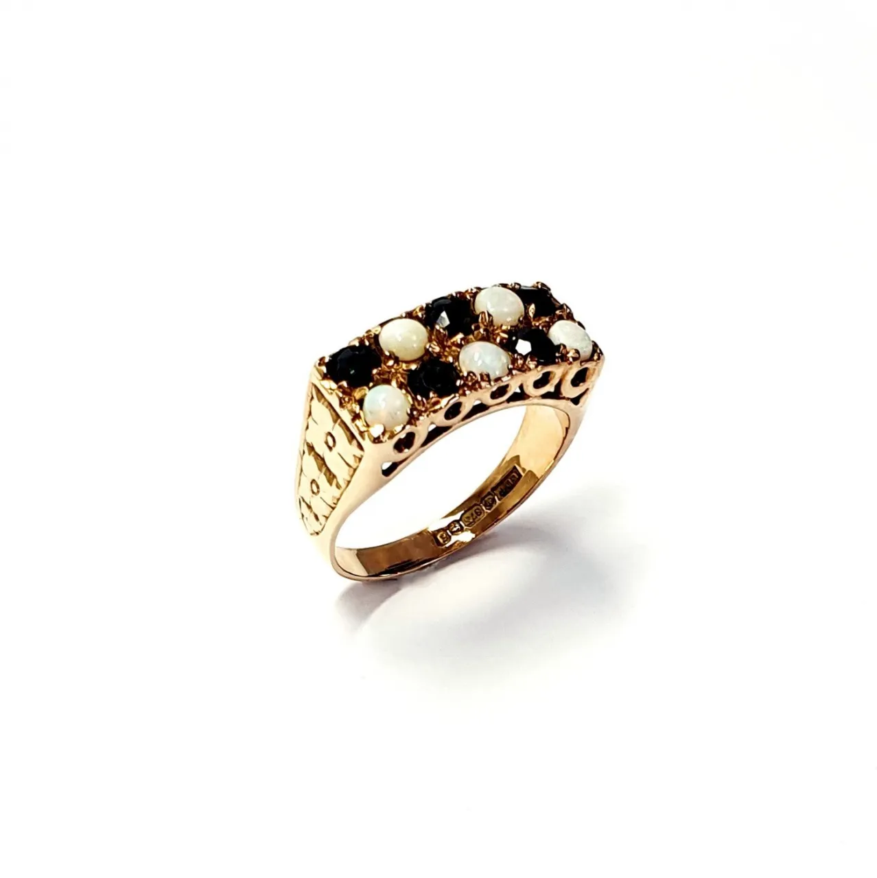 Vintage 1979 opal & dark blue sapphire 9ct gold landscape rectangular top ring measuring 18mm x 7.8mm set with five round cabochon cut opals & five round dark blue sapphires in a chequer formation with three hand engraved flowers to both—side shoulders.