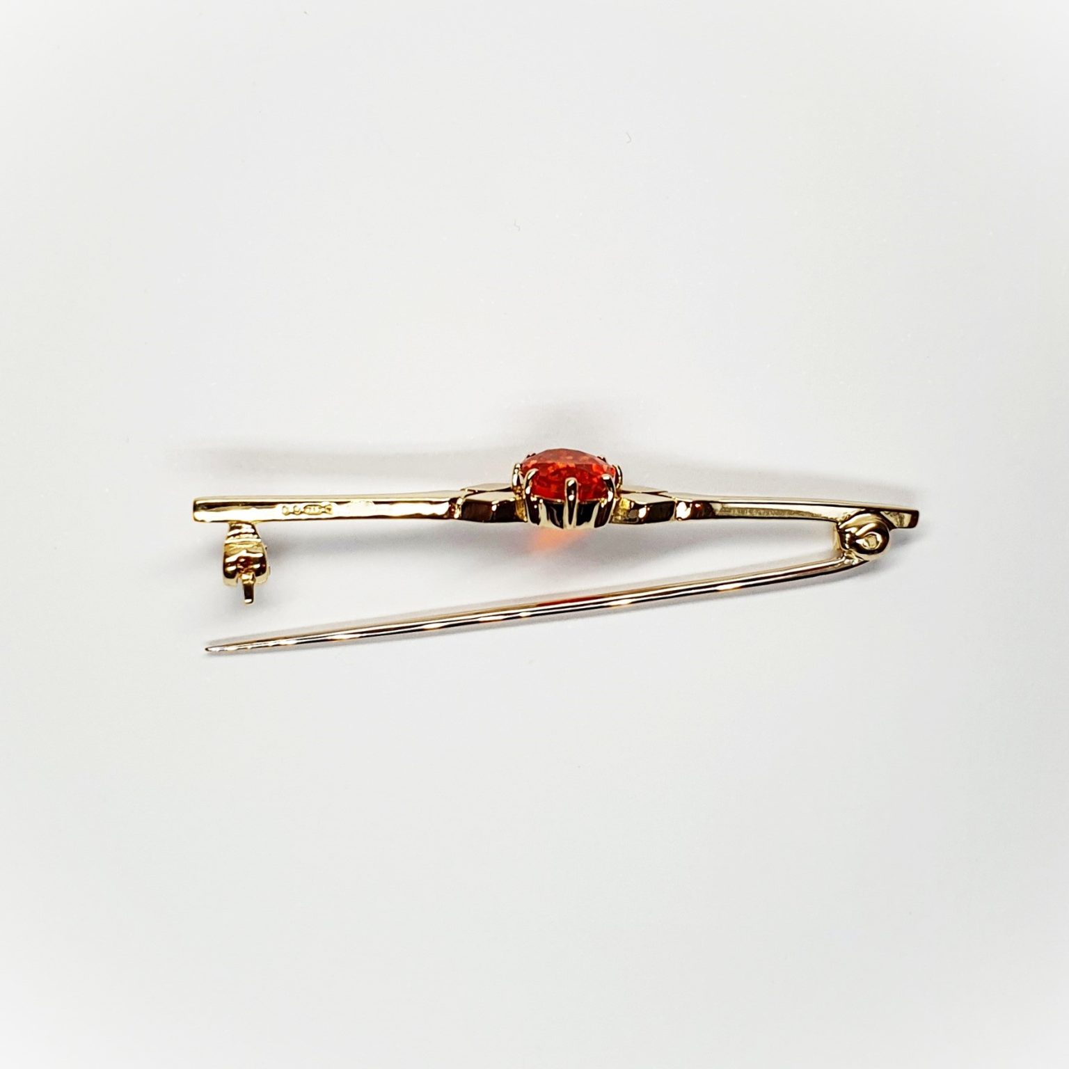 A handmade 9ct yellow gold bar brooch 52mm long set with a gorgeous top quality oval fire opal measuring 8.6mm x 7mm portrait set to the middle of the bar with three 9ct gold diamond shapes to each side of the stone with a straight pin to the back with a swivel safety catch.
