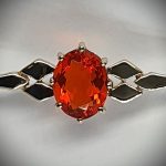 A handmade 9ct yellow gold bar brooch 52mm long set with a gorgeous top quality oval fire opal measuring 8.6mm x 7mm portrait set to the middle of the bar with three 9ct gold diamond shapes to each side of the stone with a straight pin to the back with a swivel safety catch.