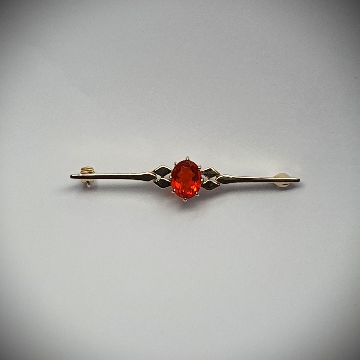 A handmade 9ct yellow gold bar brooch 52mm long set with a gorgeous top quality oval fire opal measuring 8.6mm x 7mm portrait set to the middle of the bar with three 9ct gold diamond shapes to each side of the stone with a straight pin to the back with a swivel safety catch.