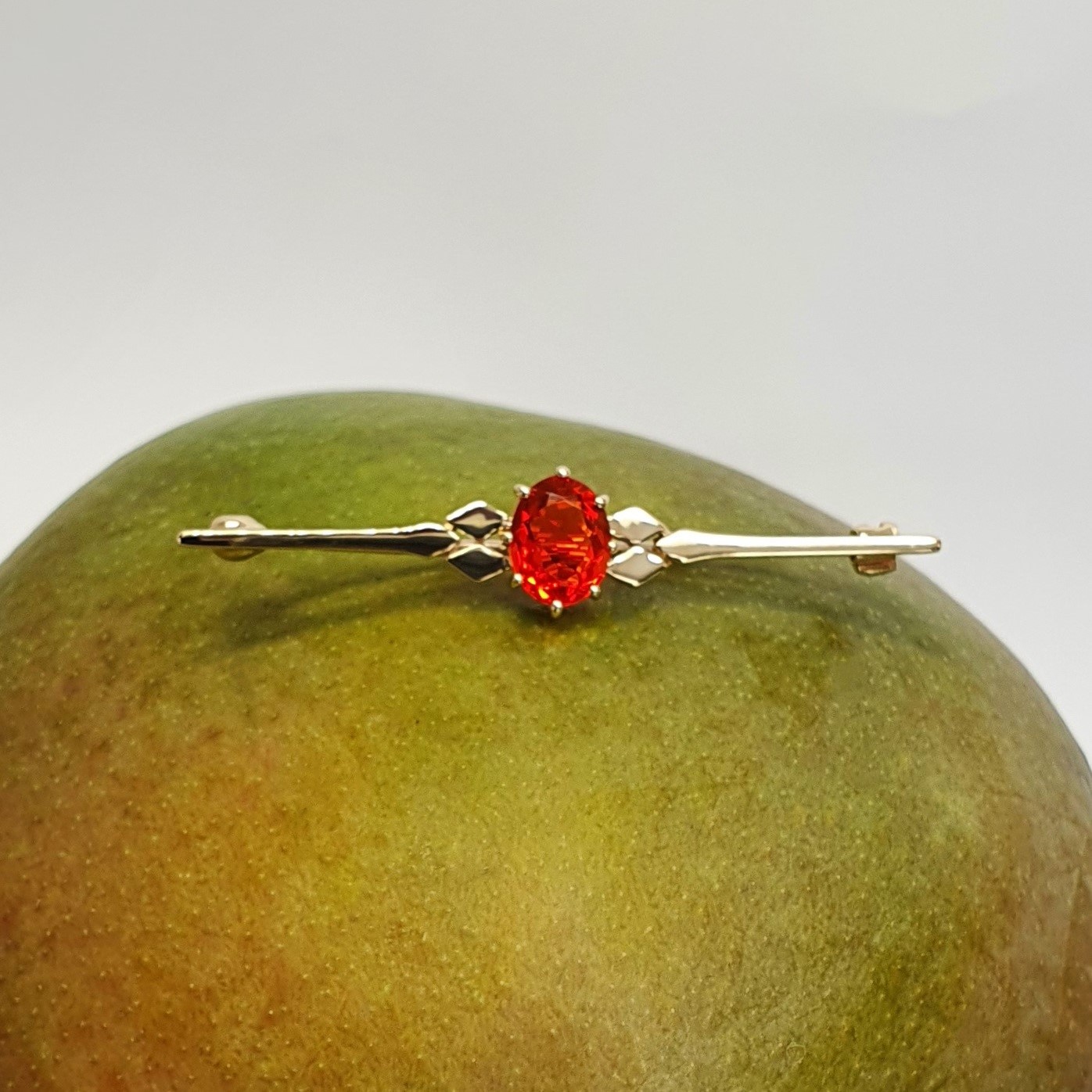 A handmade 9ct yellow gold bar brooch 52mm long set with a gorgeous top quality oval fire opal measuring 8.6mm x 7mm portrait set to the middle of the bar with three 9ct gold diamond shapes to each side of the stone with a straight pin to the back with a swivel safety catch.