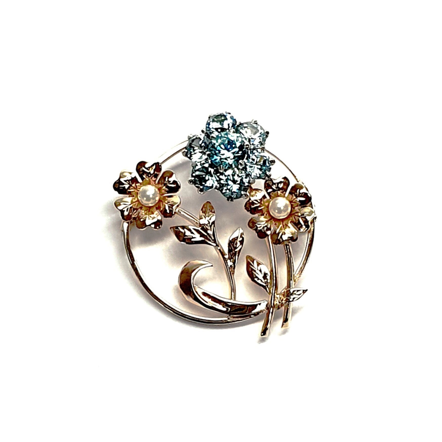 9ct Gold Blue Flower Brooch, three stems of flowers in a circle. In the centre is a flower with six round blue zircon petals set in white gold, with a six-petal 9ctyellow  gold flower on each side set with a single pearl to each centre.