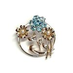 9ct Gold Blue Flower Brooch, three stems of flowers in a circle. In the centre is a flower with six round blue zircon petals set in white gold, with a six-petal 9ctyellow  gold flower on each side set with a single pearl to each centre.