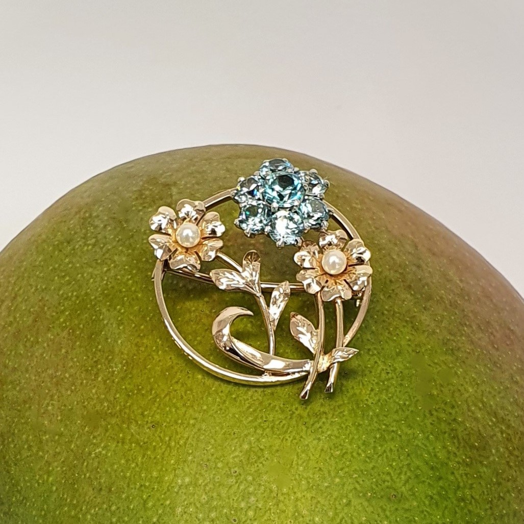 9ct Gold Blue Flower Brooch, three stems of flowers in a circle. In the centre is a flower with six round blue zircon petals set in white gold, with a six-petal 9ctyellow  gold flower on each side set with a single pearl to each centre.