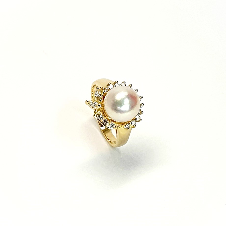 View of the top of the ring standing up and angled to the right the two marquise diamonds facing towards the front to the left of the picture They are crafted in 18ct yellow gold set with a single round 9mm cultured pearl surrounded by fifteen sparkling white round diamonds and two marquise-shaped diamonds with a total diamond weight of 0.31 carats.