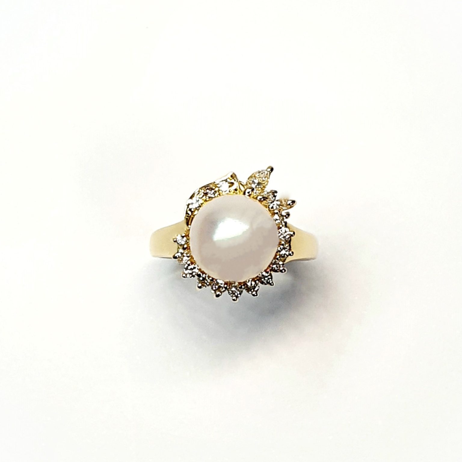 View of the top of the ring looking down on the top with the two marquise diamonds facing to the top of the picture they are crafted in 18ct yellow gold set with a single round 9mm cultured pearl surrounded by fifteen sparkling white round diamonds and two marquise-shaped diamonds with a total diamond weight of 0.31 carats.