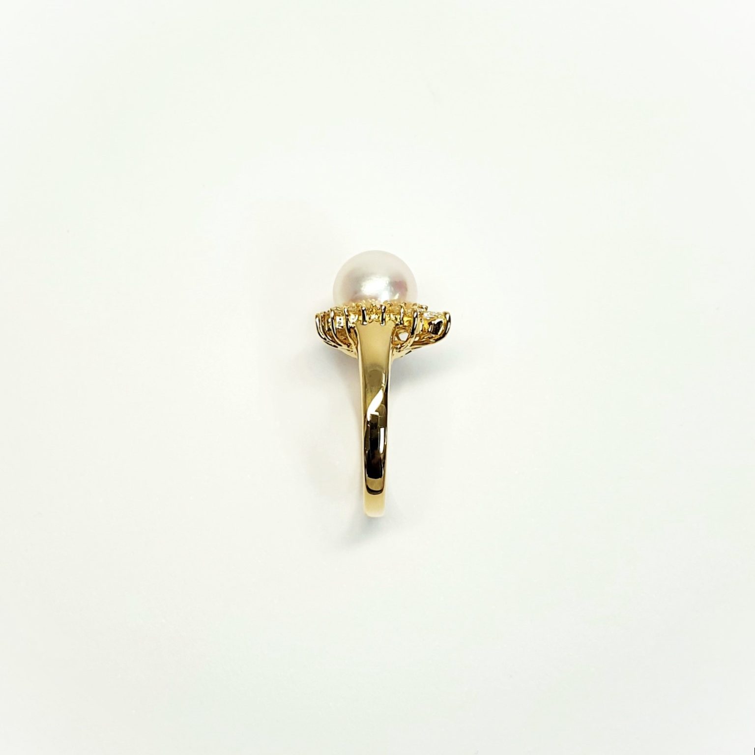 View of the side shoulder of the ring Marquise stones facing right They are crafted in 18ct yellow gold set with a single round 9mm cultured pearl surrounded by fifteen sparkling white round diamonds and two marquise-shaped diamonds with a total diamond weight of 0.31 carats.