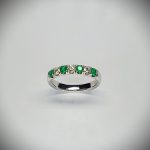 18ct White Gold Emerald & Diamond Eternity Ring RA00685 Four 2.8mm round emeralds and three 2.8mm round diamonds ring standing up to the front angled facing to the front. With a dark background.