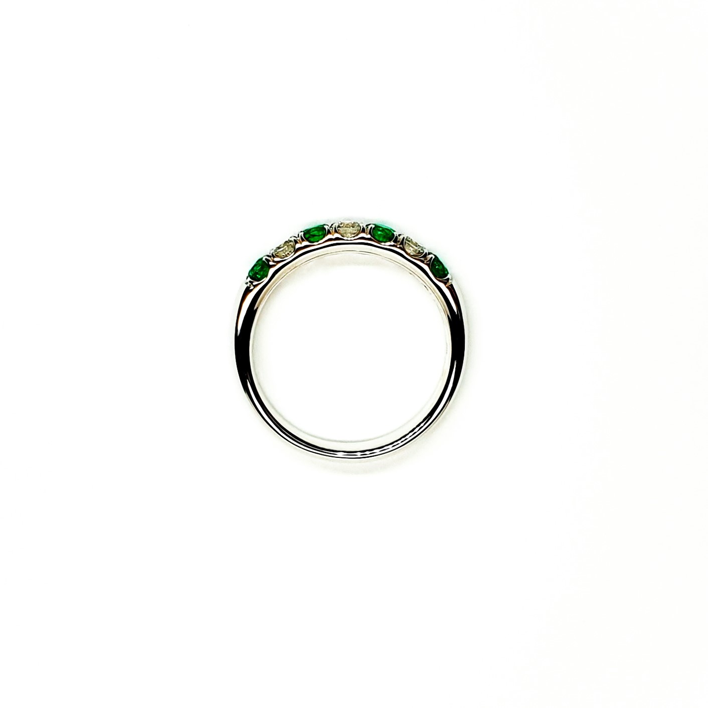 18ct White Gold Emerald & Diamond Eternity Ring RA00685 Four 2.8mm round emeralds and three 2.8mm round diamonds ring laying down side view.
