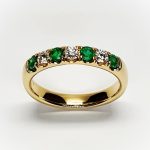 18ct yellow gold seven-stone eternity ring 3.5mm wide set with four 2.8mm round emeralds and three 2.8mm round diamonds in four claw settings