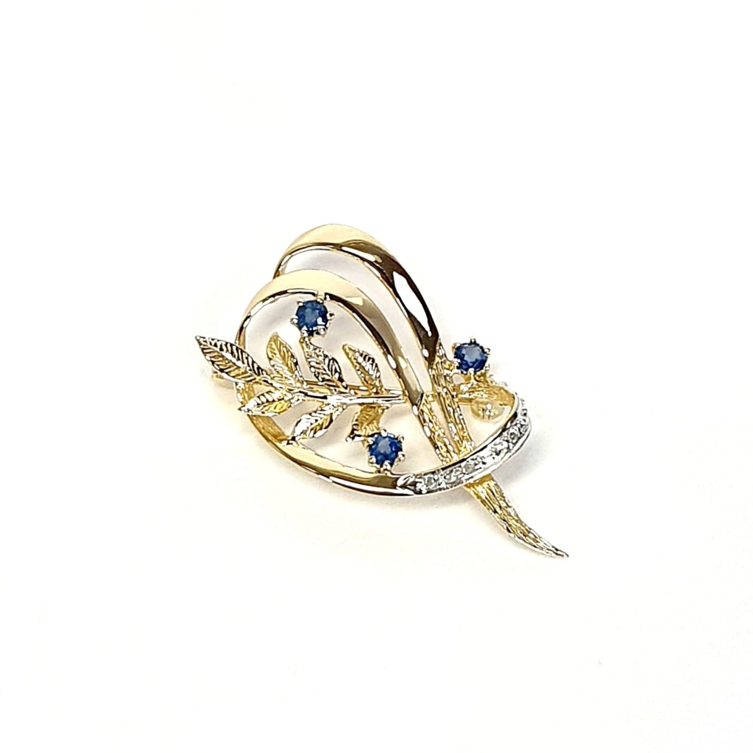 9ct yellow gold brooch with a sprig of seven leaves coming through a floral swirl of polished and barked yellow gold with three diamonds set into a small white rhodium section 
