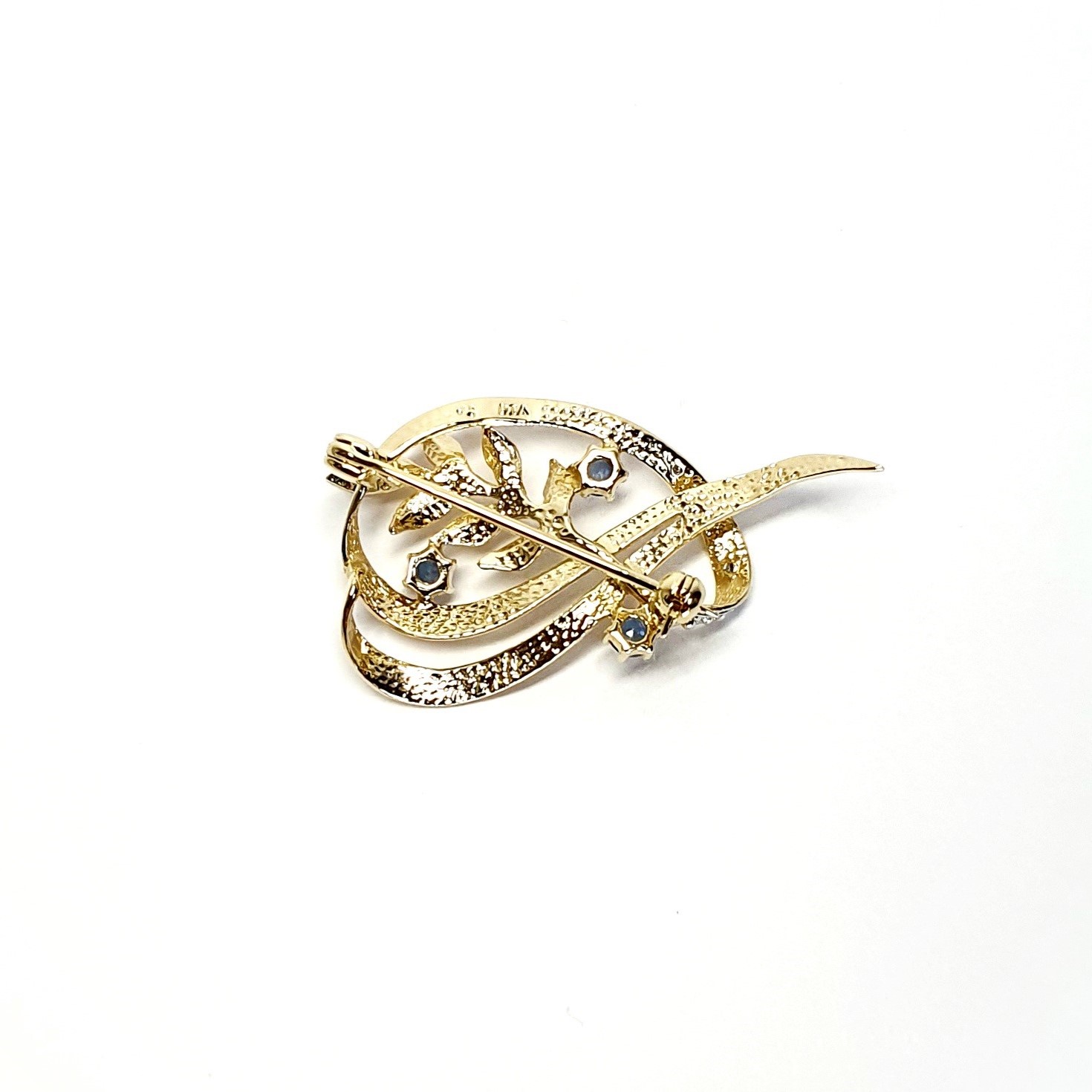 9ct yellow gold brooch with a sprig of seven leaves coming through a floral swirl of polished and barked yellow gold with three diamonds set into a small white rhodium section 