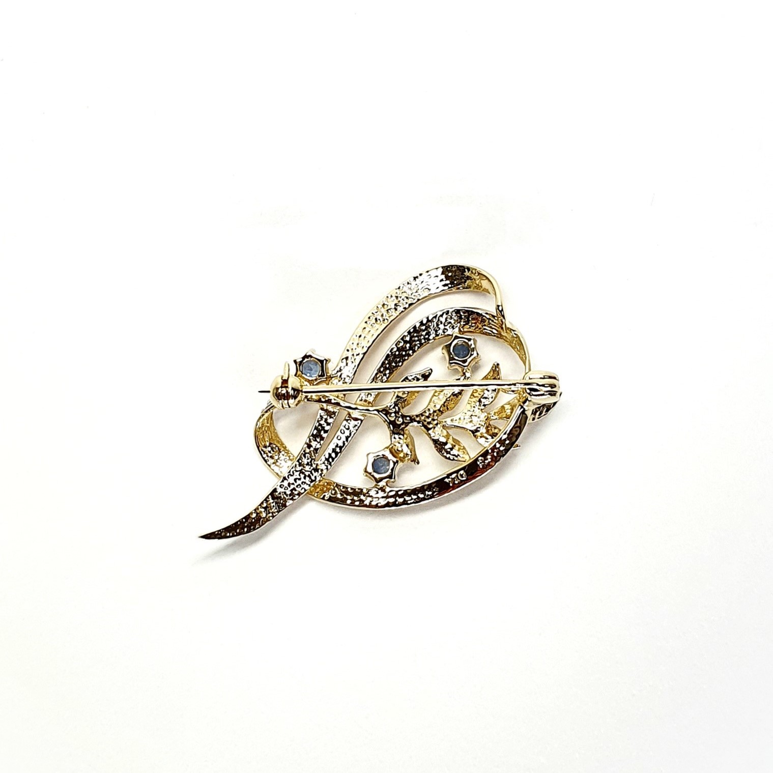 9ct yellow gold brooch with a sprig of seven leaves coming through a floral swirl of polished and barked yellow gold with three diamonds set into a small white rhodium section 