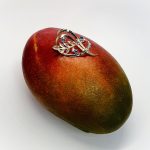 Brooch pictured sitting on a mango.