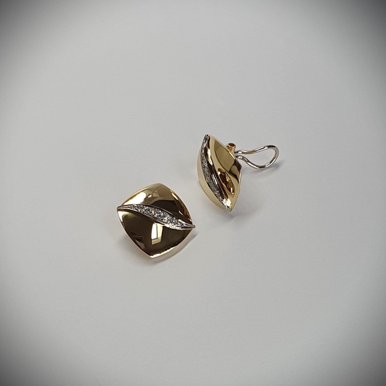 Measurements 16mm x 16mm. And 19mm corner to corner Handmade 18ct yellow gold curved cushion-shaped clip-on earrings with an 18ct white gold wave going from corner to corner set with seven graduated round white diamonds to each earring.