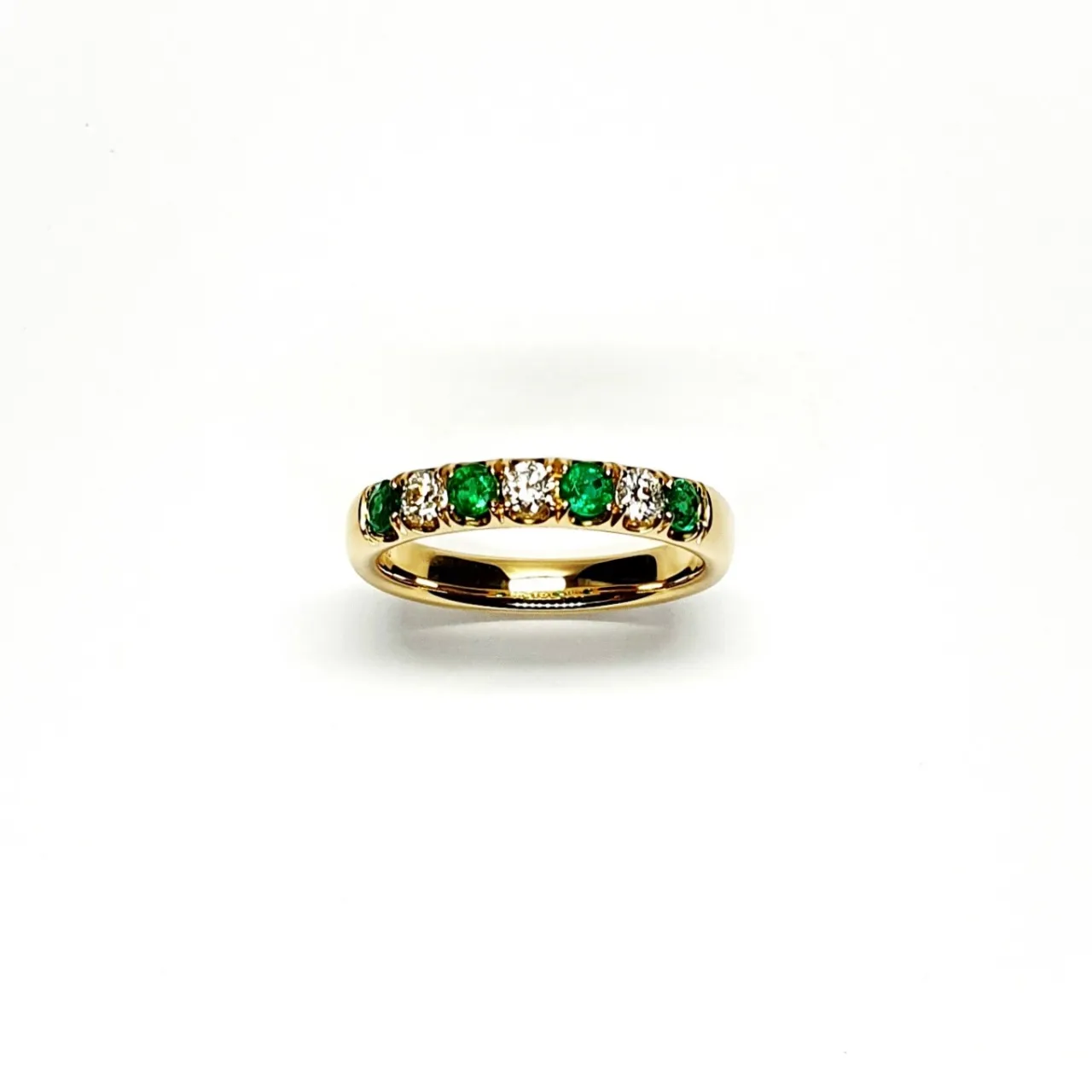 18ct yellow gold seven-stone eternity ring 3.5mm wide set with four 2.8mm round emeralds and three 2.8mm round diamonds in four claw settings