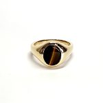 The City of London Jewellers presents the Eyemouth heavy 9ct yellow gold 12mm x 10mm oval Tigers Eye with a slightly curved top rub-over set into a plain polished signet ring, angled view laying down from the front.