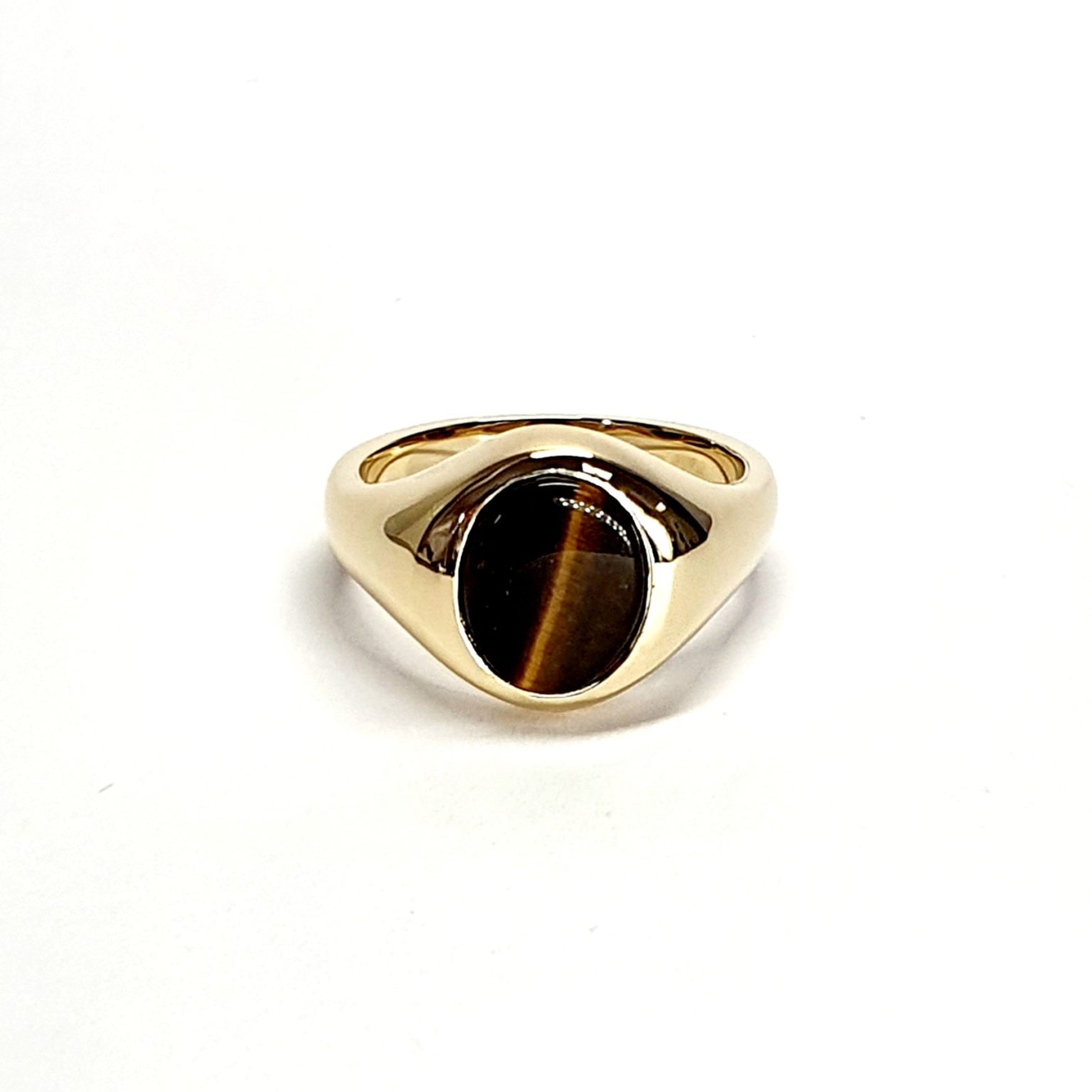 The City of London Jewellers presents the Eyemouth heavy 9ct yellow gold 12mm x 10mm oval Tigers Eye with a slightly curved top rub-over set into a plain polished signet ring, angled view laying down from the front.