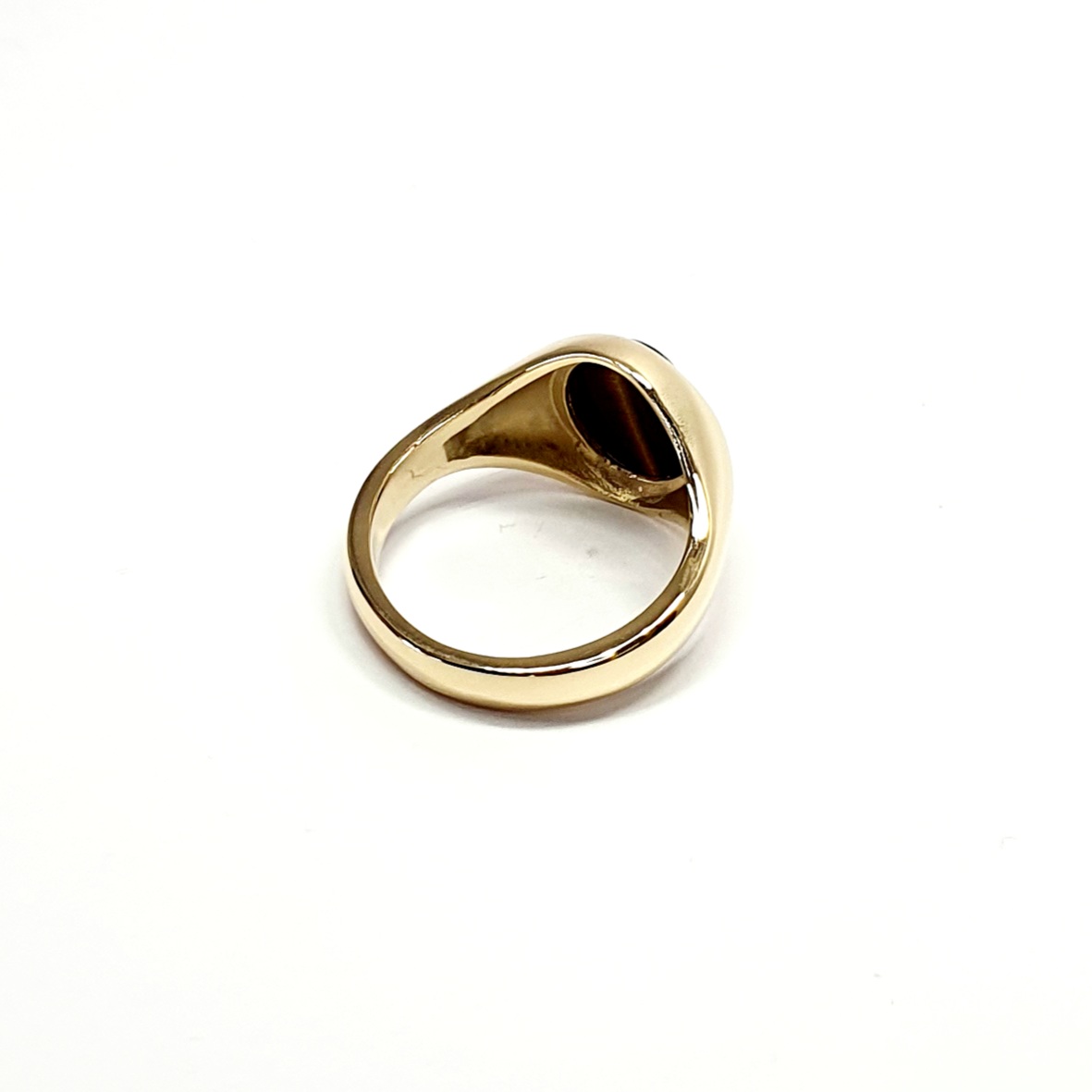 The City of London Jewellers presents the Eyemouth heavy 9ct yellow gold 12mm x 10mm oval Tigers Eye with a slightly curved top rub-over set into a plain polished signet ring, angled view laying down from the back.