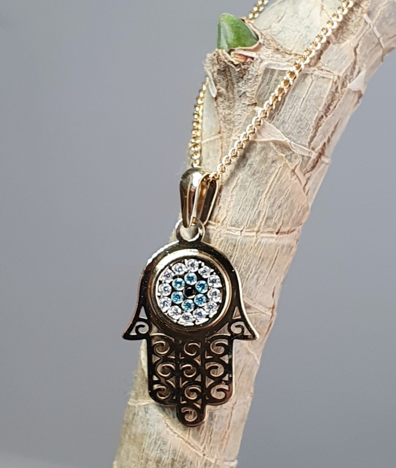 9ct yellow gold filigree style evil eye hamsa pendant and chain/necklace pendant height, including saddle bail 23.6mm width 12.5mm evil-eye set with a single black CZ pupil surrounded with six blue CZs and twelve white CZs.