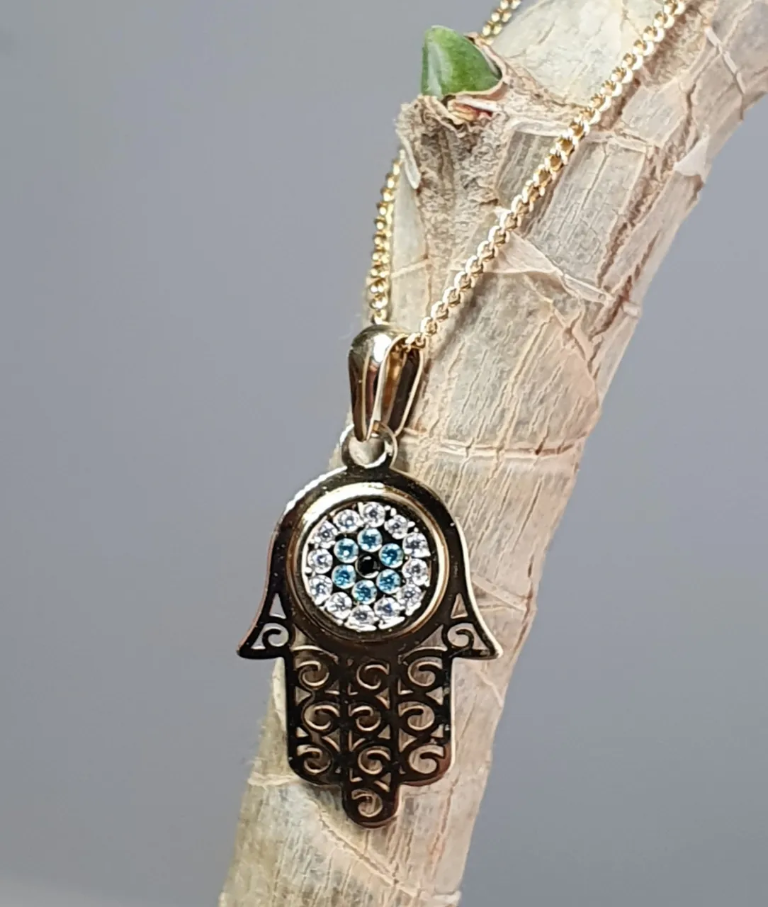 9ct yellow gold filigree style evil eye hamsa pendant and chain/necklace pendant height, including saddle bail 23.6mm width 12.5mm evil-eye set with a single black CZ pupil surrounded with six blue CZs and twelve white CZs.