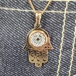 9ct yellow gold filigree style evil eye hamsa pendant and chain/necklace pendant height, including saddle bail 23.6mm width 12.5mm evil-eye set with a single black CZ pupil surrounded with six blue CZs and twelve white CZs.