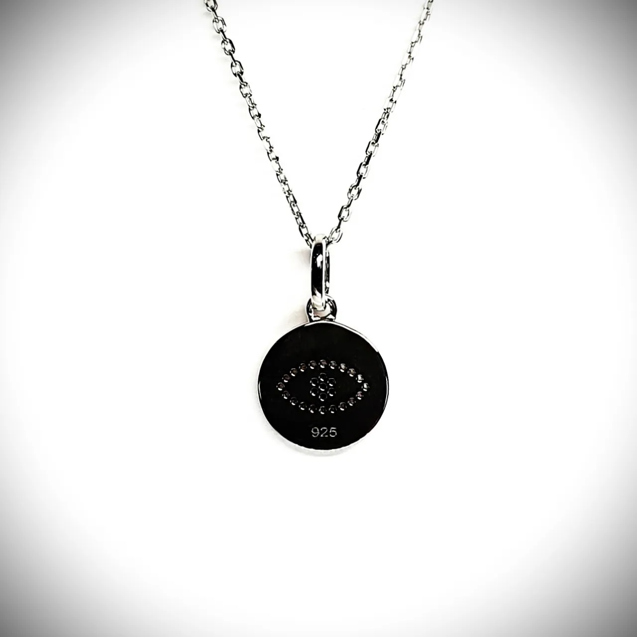 A round disc silver evil eye necklace/pendant made in real sterling silver with sparkling blue & white cubic zirconia with a highly polished finish view of the back.