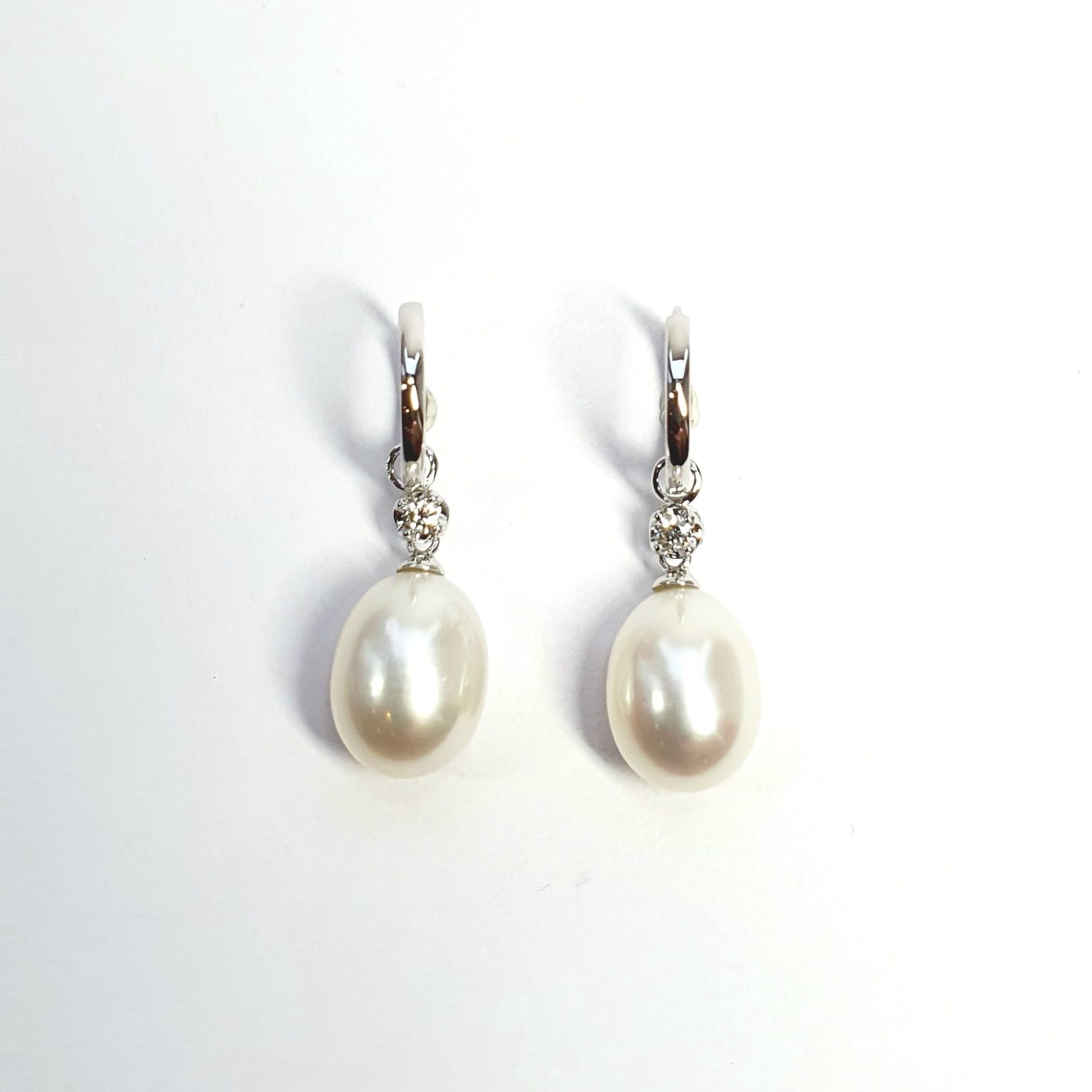 18ct white gold polished huggie loop/hoop earrings leading to a single round diamond and then onto  a single oval pearl drop.