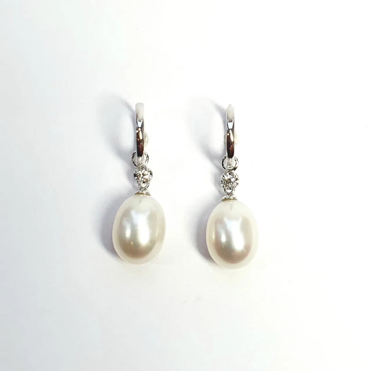18ct white gold polished huggie loop/hoop earrings leading to a single round diamond and then onto  a single oval pearl drop.