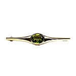9ct yellow gold pre-loved bar brooch with an oval peridot gemstone in a landscape rub-over setting with a straight pin and a swivel safety catch.
