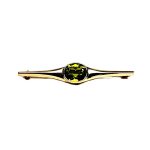 9ct yellow gold pre-loved bar brooch with an oval peridot gemstone in a landscape rub-over setting with a straight pin and a swivel safety catch.