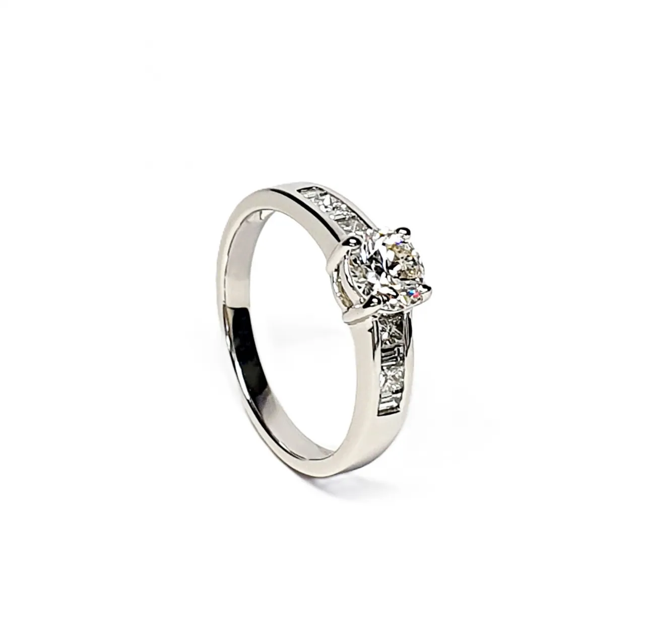The Lambeth Platinum Diamond Engagement Ring RPT00045 The centre is set with a 0.70ct round brilliant-cut diamond of Colour H clarity SI1, which has an excellent cut, proportions, and symmetry. The side shoulders are channel set with a total of four princess-cut diamonds and four baguette-cut diamonds. The total diamond weight is 1.08 carats.
