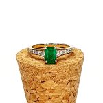 Emerald ring resting on cork surface with warm lighting