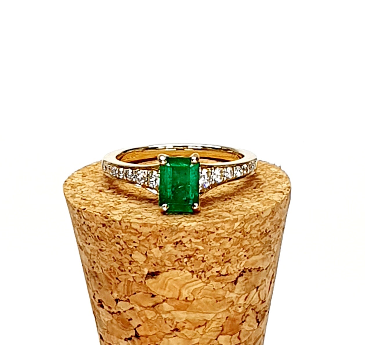 Emerald ring resting on cork surface with warm lighting