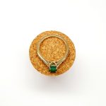 Step cut Emerald Ring with Diamonds to Each Side laying flat on a cork
