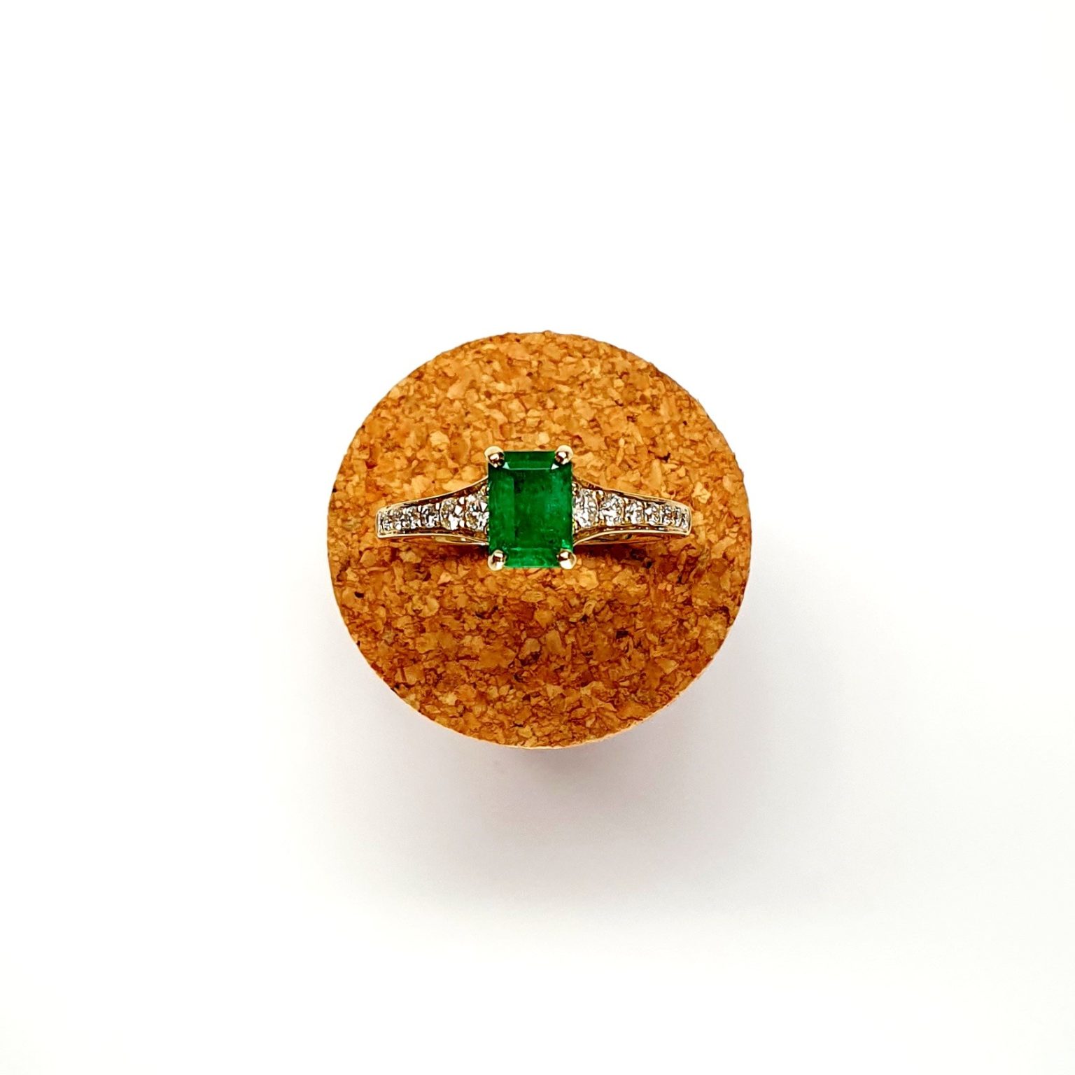 Top view of step cut emerald ring on a cork